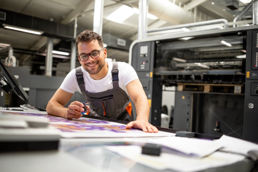 Printing press operator working with modern offset machine in UK print facility